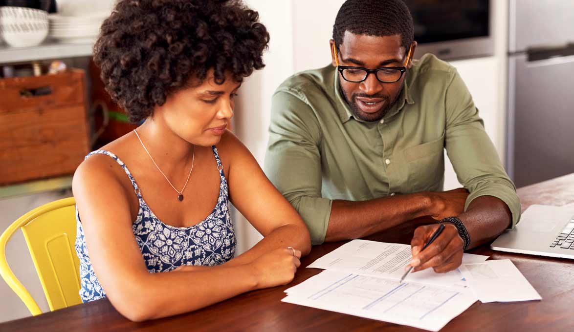 Couple at kitchen table reviewing home refinance paperwork